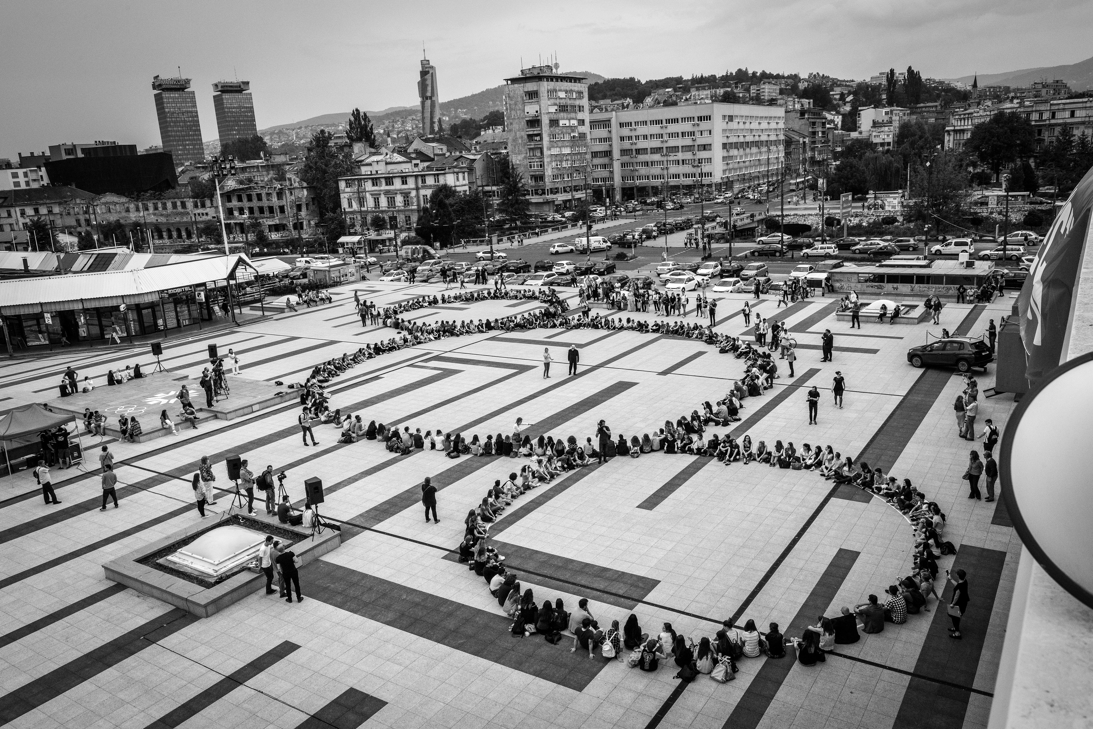 Black and white photo of people standing in Michelangelo Pistoletto Third Paradise symbol, Sarajevo